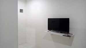 Una habitación pequeña con paredes blancas y un televisor de pantalla plana montado en un estante blanco.