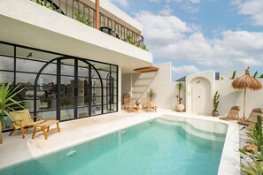 A modern pool area with lounge chairs and a glass-enclosed room. - Villa The Santé (Canggu)