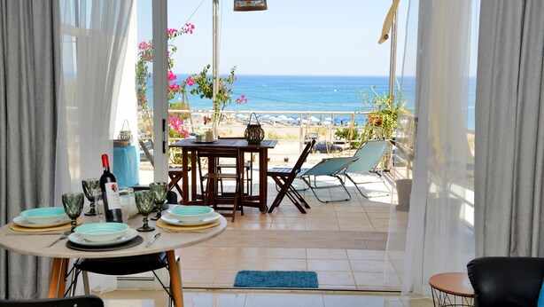 A dining area with a table set for two, overlooking a beach. - Studio Mare Faliraki, Beachfront (Faliraki)