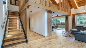 Un interior modern amb una escala de fusta que condueix a un balcó.