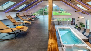 Un espace spa comprenant un bain à remous, des chaises longues et une vue sur l’extérieur.