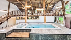 Un espace piscine intérieur moderne avec un plafond en bois, un jacuzzi et un escalier doté d’une rampe en bois.