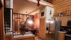 Une cuisine avec un intérieur en bois, un réfrigérateur et un coin repas comprenant une table et des chaises.
