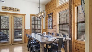 Un coin repas avec une table et des chaises en bois, un lustre et une enseigne indiquant « Bear Ridge Bine and Reine ».