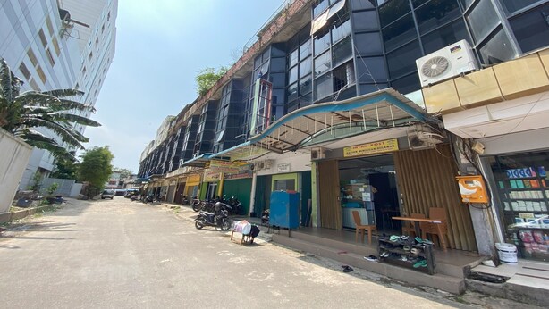 A street view with buildings, a motorcycle, and a shop with a sign. - Hotel O Intan HomestayNearAnugrah Sinar Lautan (Batam)