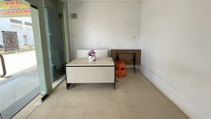 A room with a bed, a small table with a vase, and a stool. - Hotel O Intan HomestayNearAnugrah Sinar Lautan (Batam)