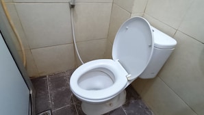 A small bathroom with a white toilet, a wall-mounted toilet paper holder, and a tiled floor. - Hotel O Aulia Residence (Rembang)