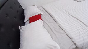 A bed with white bedding and a red pillow, a dark headboard, and a white wall. - Hotel O Aulia Residence (Rembang)