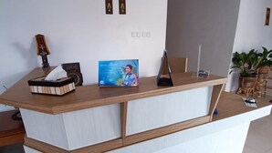 A reception desk with a tissue box, a framed photo, and a brochure. - Hotel O Aulia Residence (Rembang)