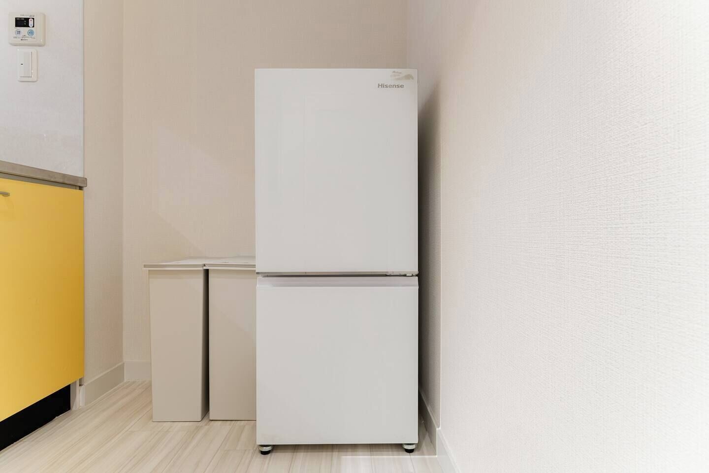 A white Hisense refrigerator in a kitchen with a yellow cabinet and a small white table.
