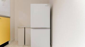 A white Hisense refrigerator in a kitchen with a yellow cabinet and a small white table.