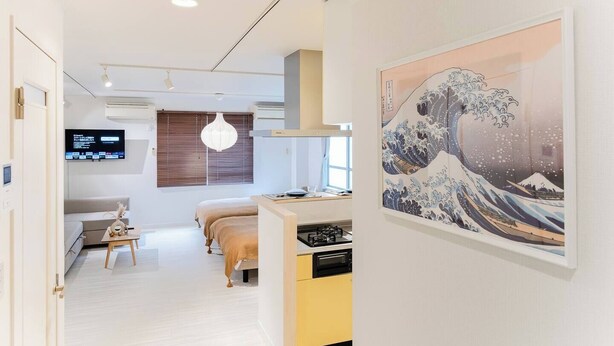 A modern hotel room with a bed, bedside table, and a large painting of a wave.