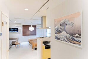 Una habitación de hotel moderna con una cama, mesita de noche y un cuadro grande de una ola.