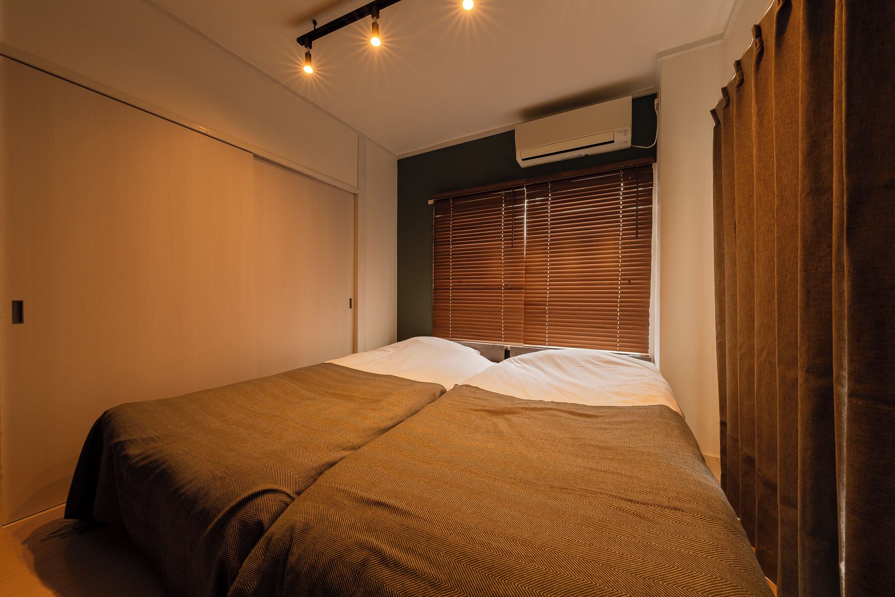 A bedroom with two beds, a ceiling light fixture, and an air conditioning unit.