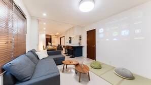 A modern living room with a sofa, coffee table, and a dining area in the background.