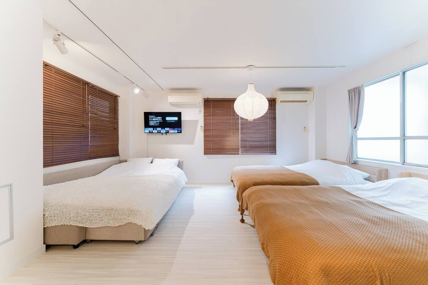 Una habitación de hotel moderna con dos camas, un televisor en la pared y amplios ventanales.
