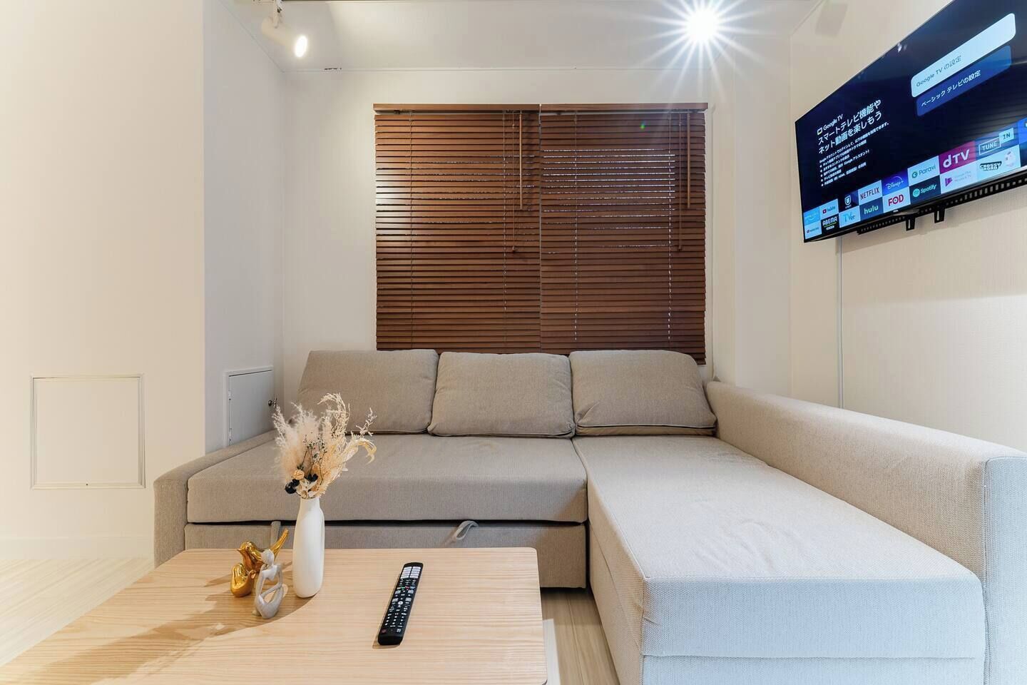 A modern living room with a beige sofa, a wooden coffee table, and a mounted TV displaying various streaming services.
