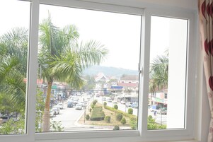 Vista desde una ventana a una calle concurrida, con palmeras y edificios.