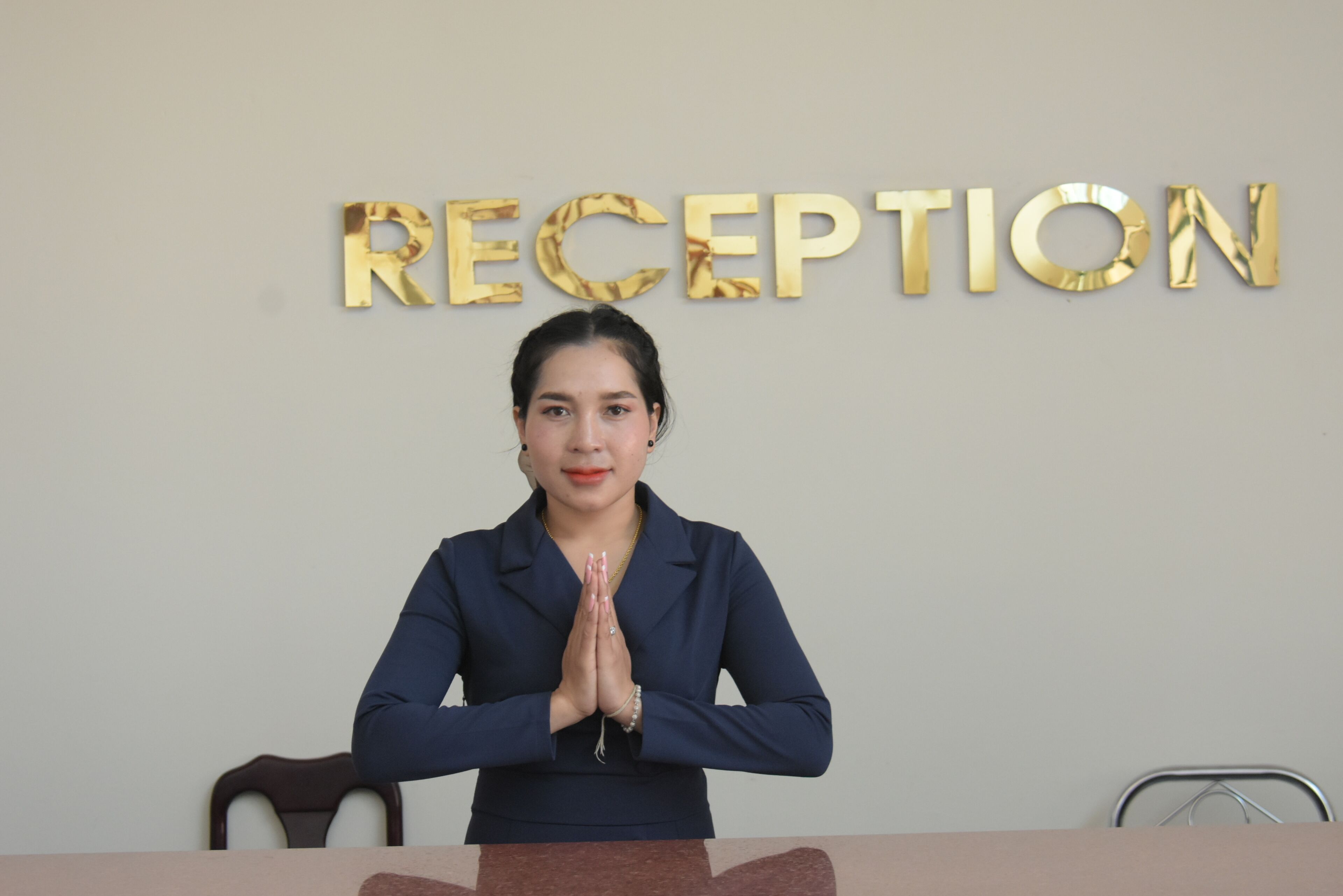 Una persona sentada en un escritorio, con un letrero que dice "RECEPTION" al fondo.