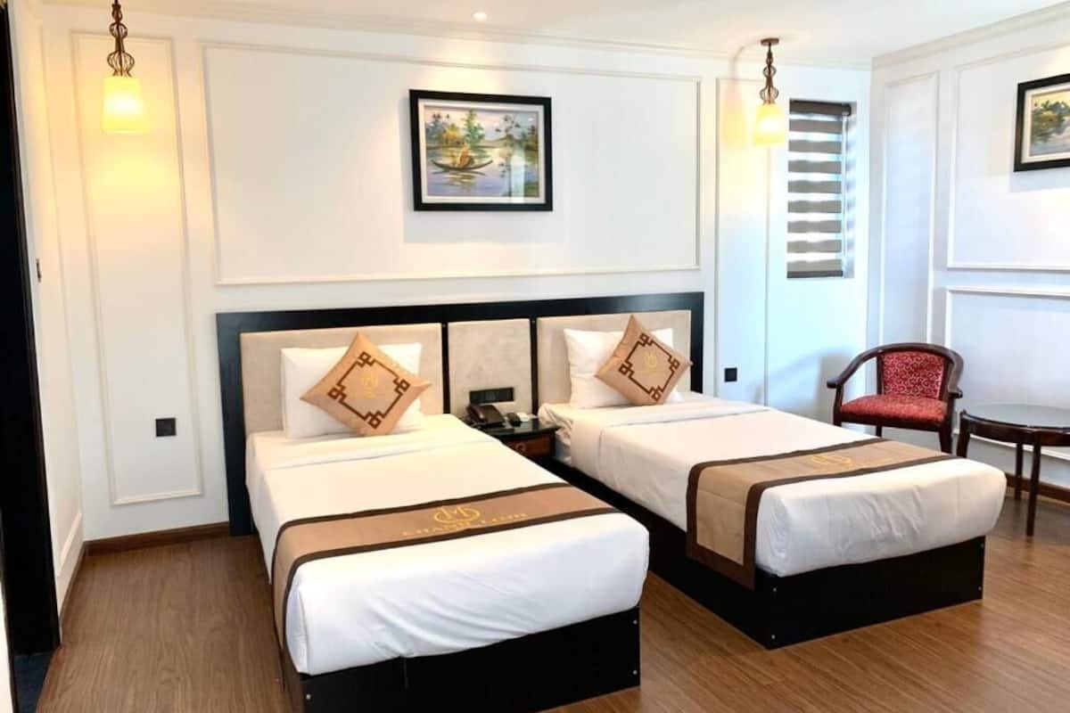 Habitació d'hotel amb dos llits, una cadira i una taula.