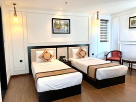 Una habitación de hotel con dos camas, una silla y una mesa.