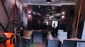 A modern lounge area with wicker furniture, a bar area, and artificial grass flooring. - Mclorrets Suites (Enugu)