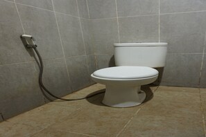 A toilet with a hose in a tiled bathroom.