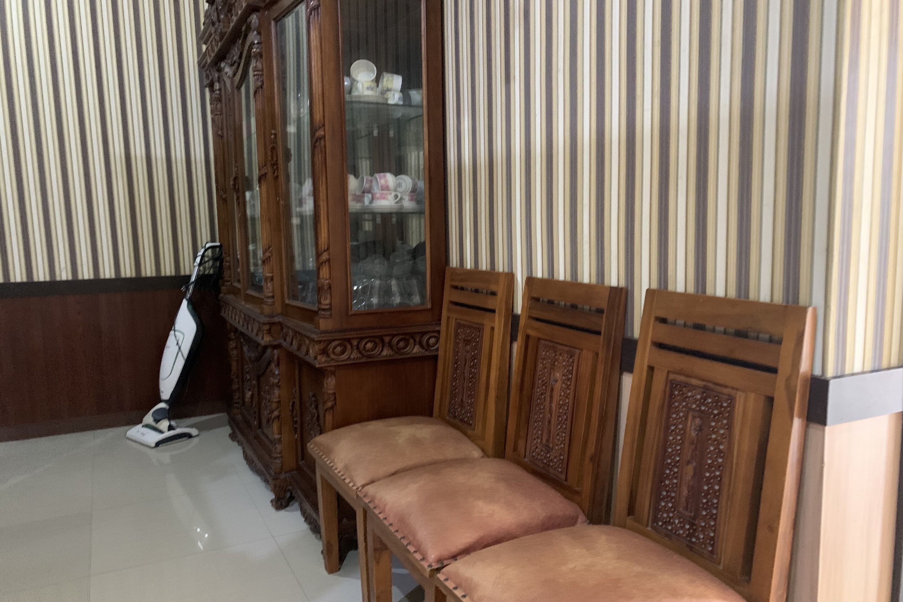 Una habitación con un armario de madera, un banco y un aspirador.