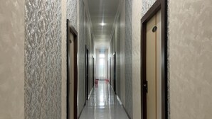 A long, narrow hallway with patterned walls and doors on either side. - Hotel O Kost Hidayat Syariah (Palopo)