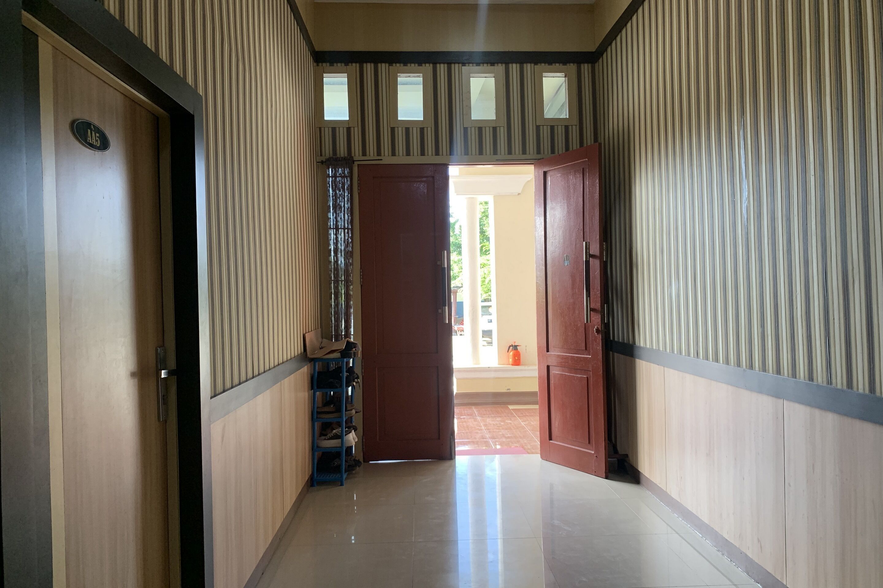 A hallway with striped walls, a wooden door labeled "A5", and a blue shoe rack.