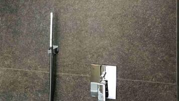 Un espacio de ducha con un cabezal de ducha tipo lluvia y otro cabezal de ducha manual fijado a la pared.