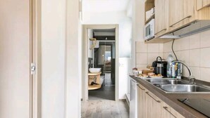 Una cocina estrecha con armarios de madera, un lavamanos de acero inoxidable y un microondas sobre la encimera.