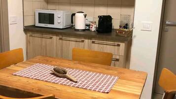 A compact kitchen with wooden cabinets, a microwave, a kettle, and a coffee maker on the countertop.
