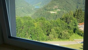 Vista desde una ventana de un paisaje montañoso con una carretera y edificios a lo lejos.