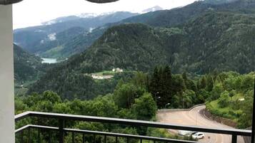 Un balcón con vista a un camino serpenteante y un valle con un lago.