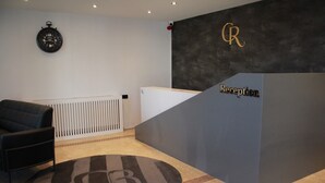 A reception area with a dark grey counter, a clock on the wall, and a radiator.