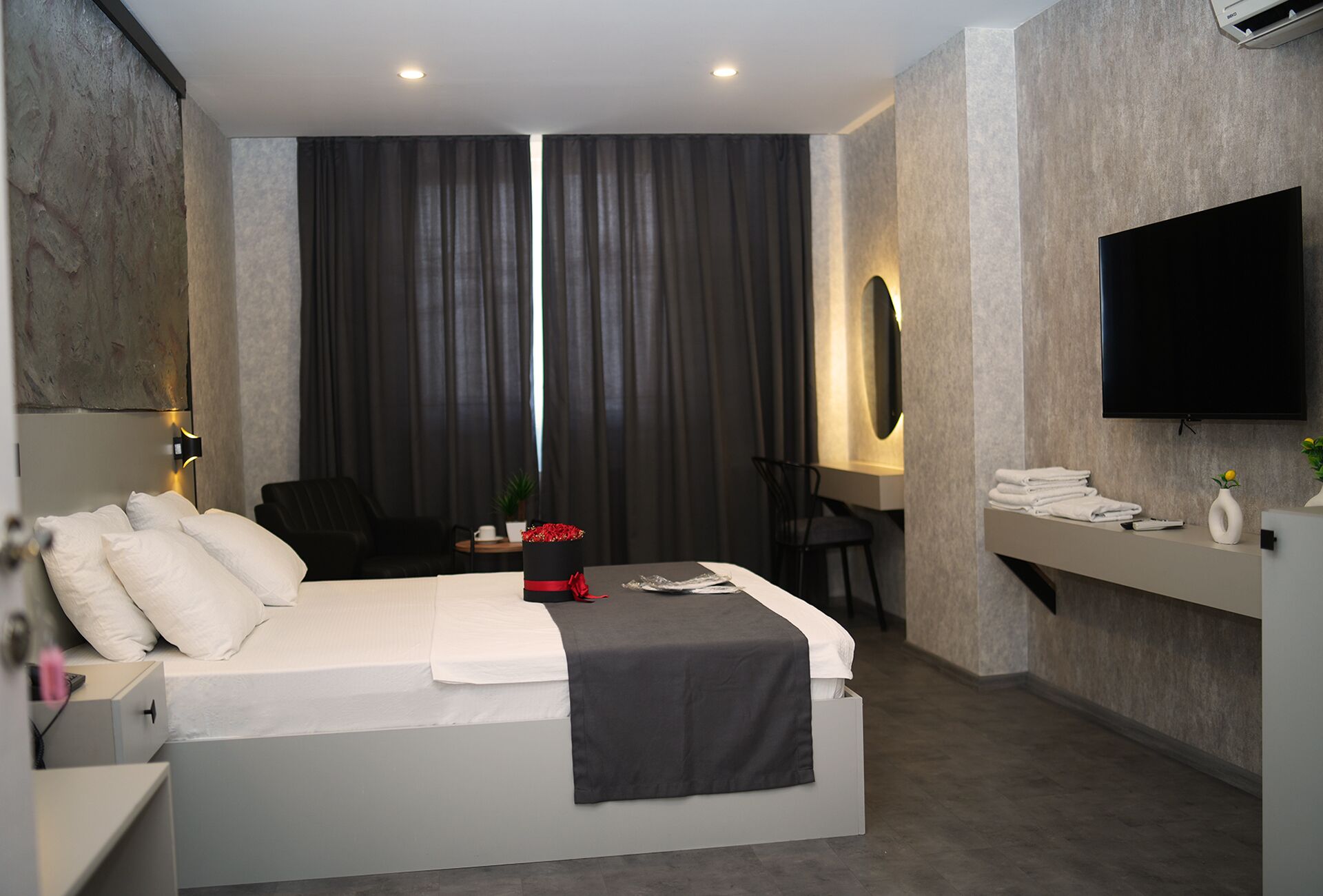 Una habitación de hotel moderna con cama, escritorio, silla, televisor y zona de baño.
