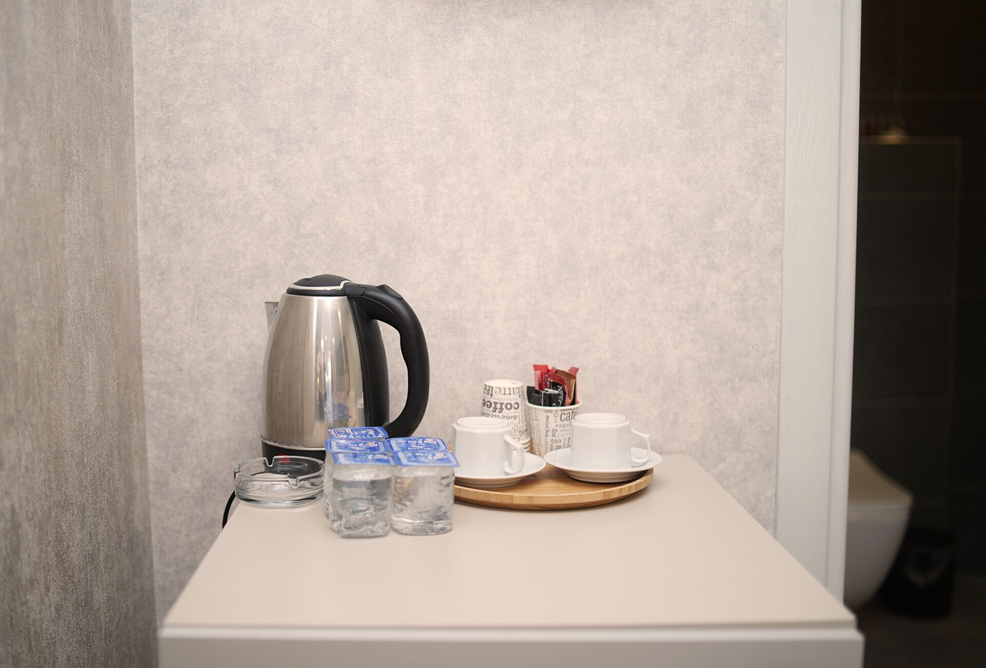 Un pequeño espacio kitchenette equipado con tetera, tazas y una bandeja.