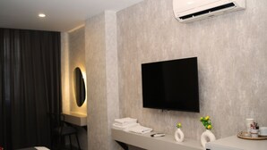 A modern bathroom with a built-in sink, a mirror, a flat-screen TV, and a towel rack.