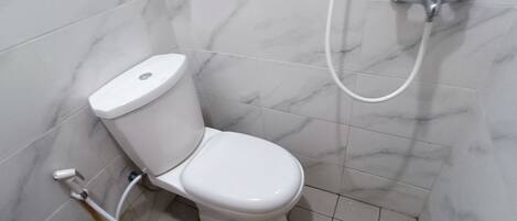 Un baño con inodoro, ducha y pared con azulejos de mármol.