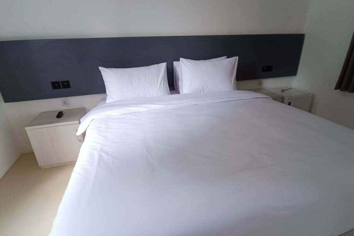 A neatly made bed with white linens and a dark headboard in a hotel room.