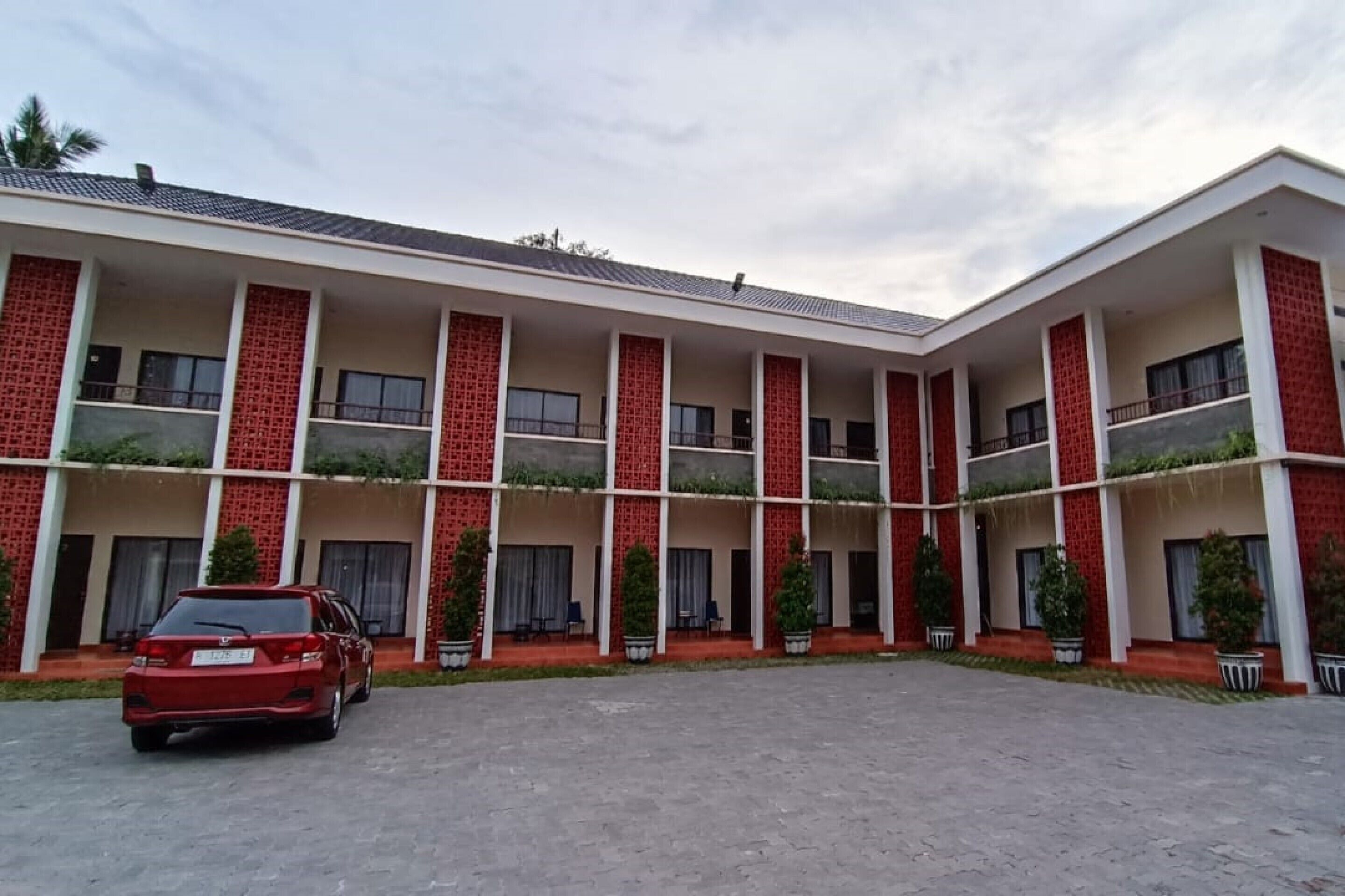 A multi-story hotel with a central courtyard, balconies, and potted plants.