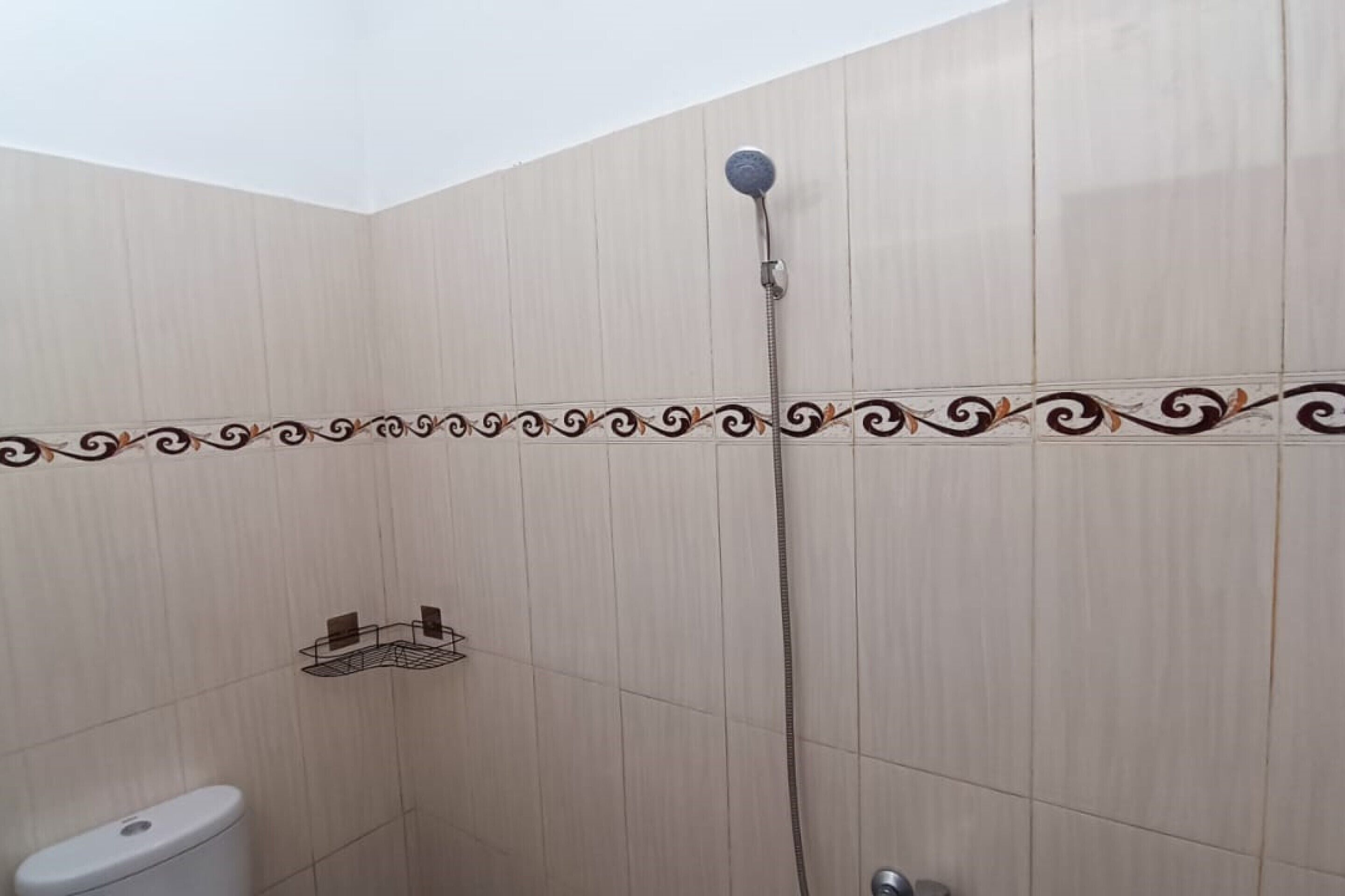 Zona de ducha con cabezal de ducha empotrado, inodoro y toallero.