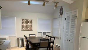 Une cuisine équipée d’une table à manger, de chaises, d’un ventilateur de plafond et d’un réfrigérateur.