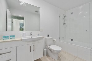 Une salle de bain moderne équipée d’un lavabo, de toilettes et d’une douche à parois de verre.