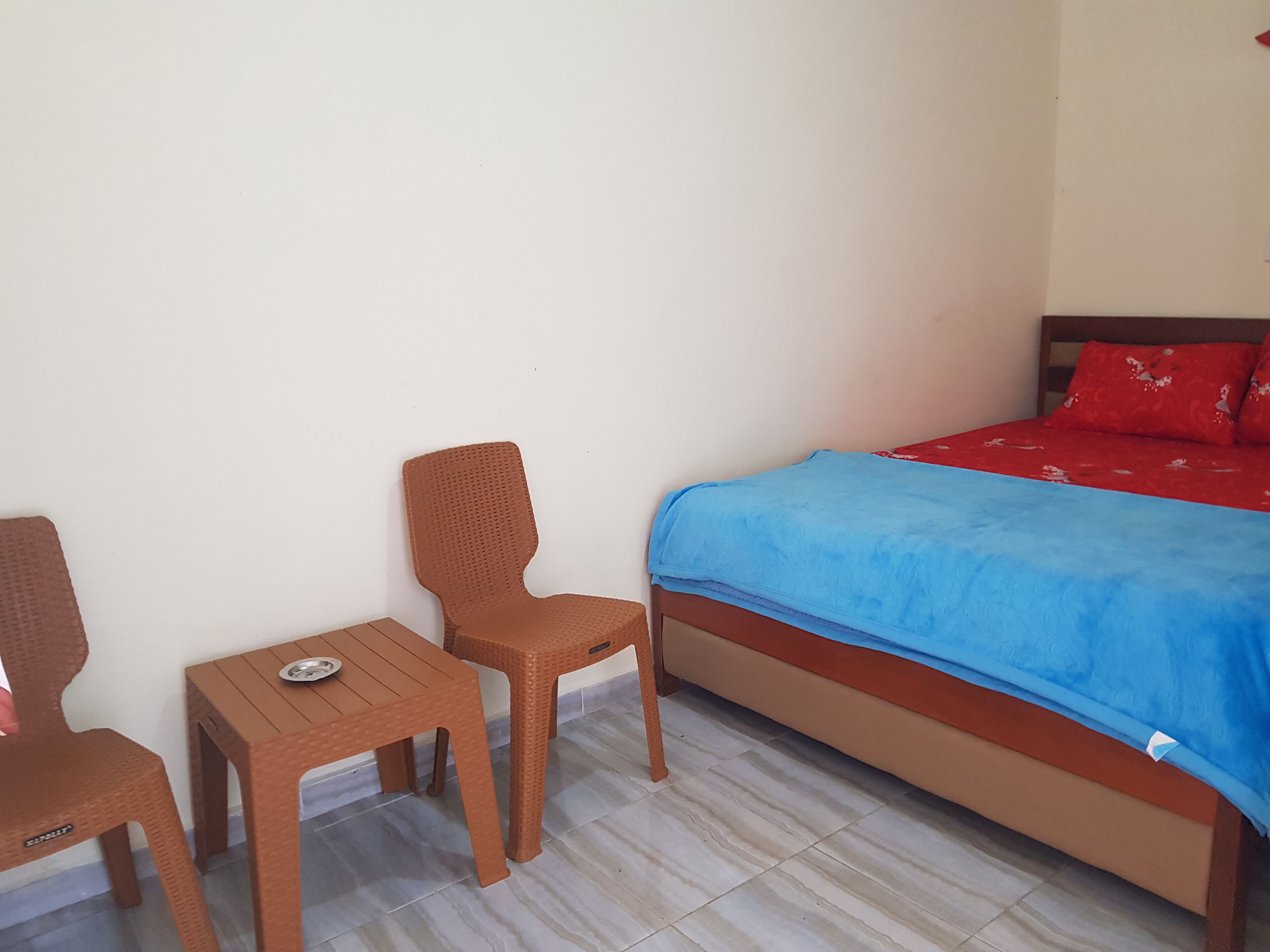 A bedroom with a bed, a small table, and two chairs.