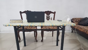 Un mostrador de recepción con una computadora portátil, un letrero que dice "RECEPTION" y un mantel estampado.