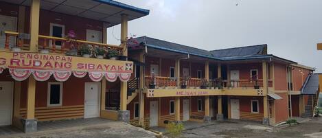 A building with multiple balconies and a sign that reads "PENGINAPAN GRUDANG SIBAYAK".