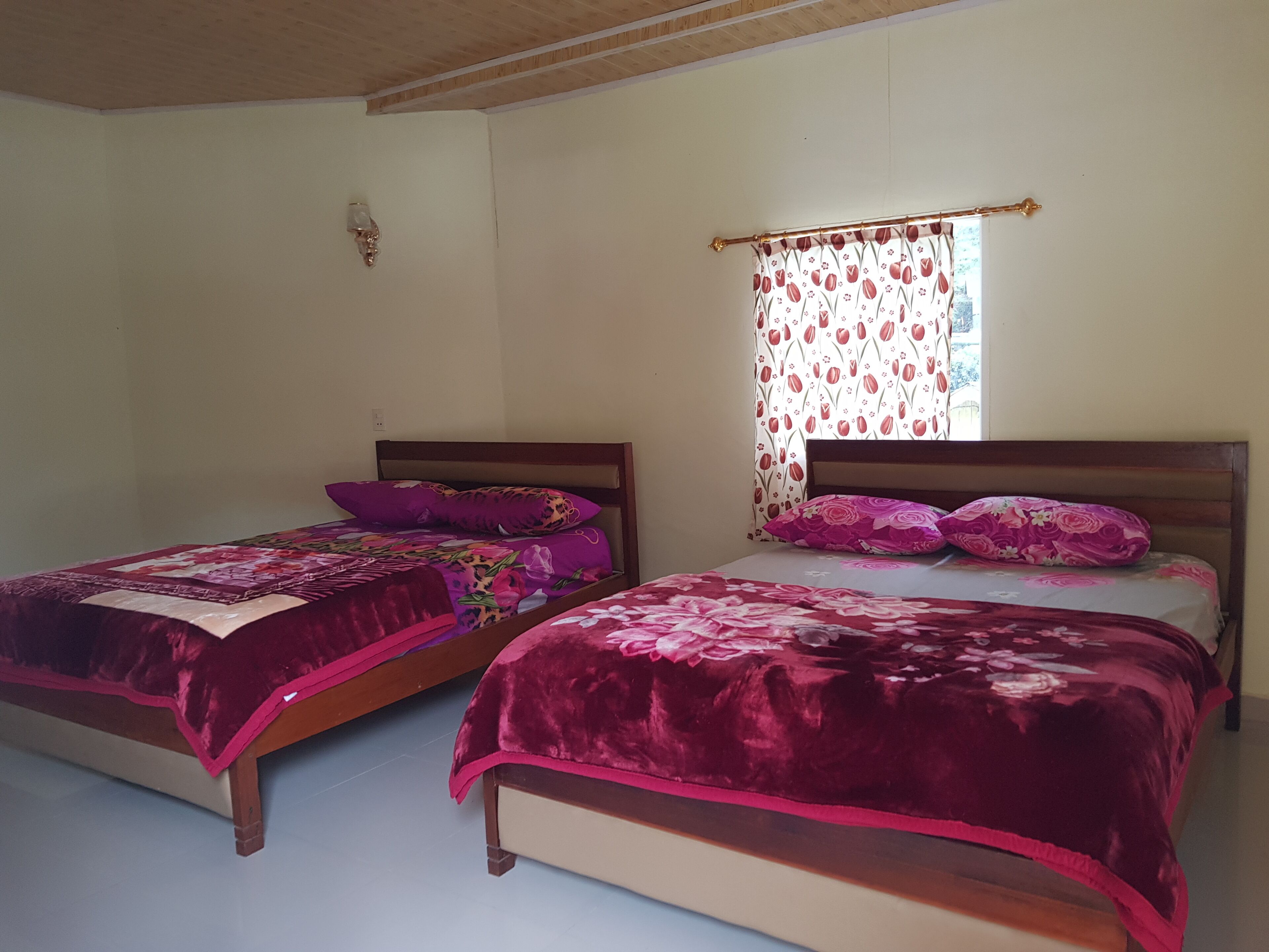 Een slaapkamer met twee bedden, elk met een houten hoofdbord en een bloemenbedekking.