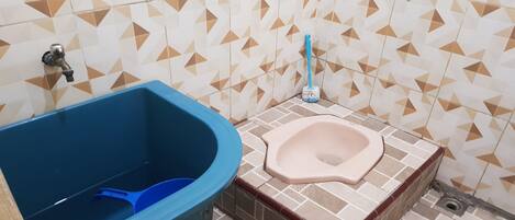 A bathroom with a blue bucket, a toilet, and a mop.